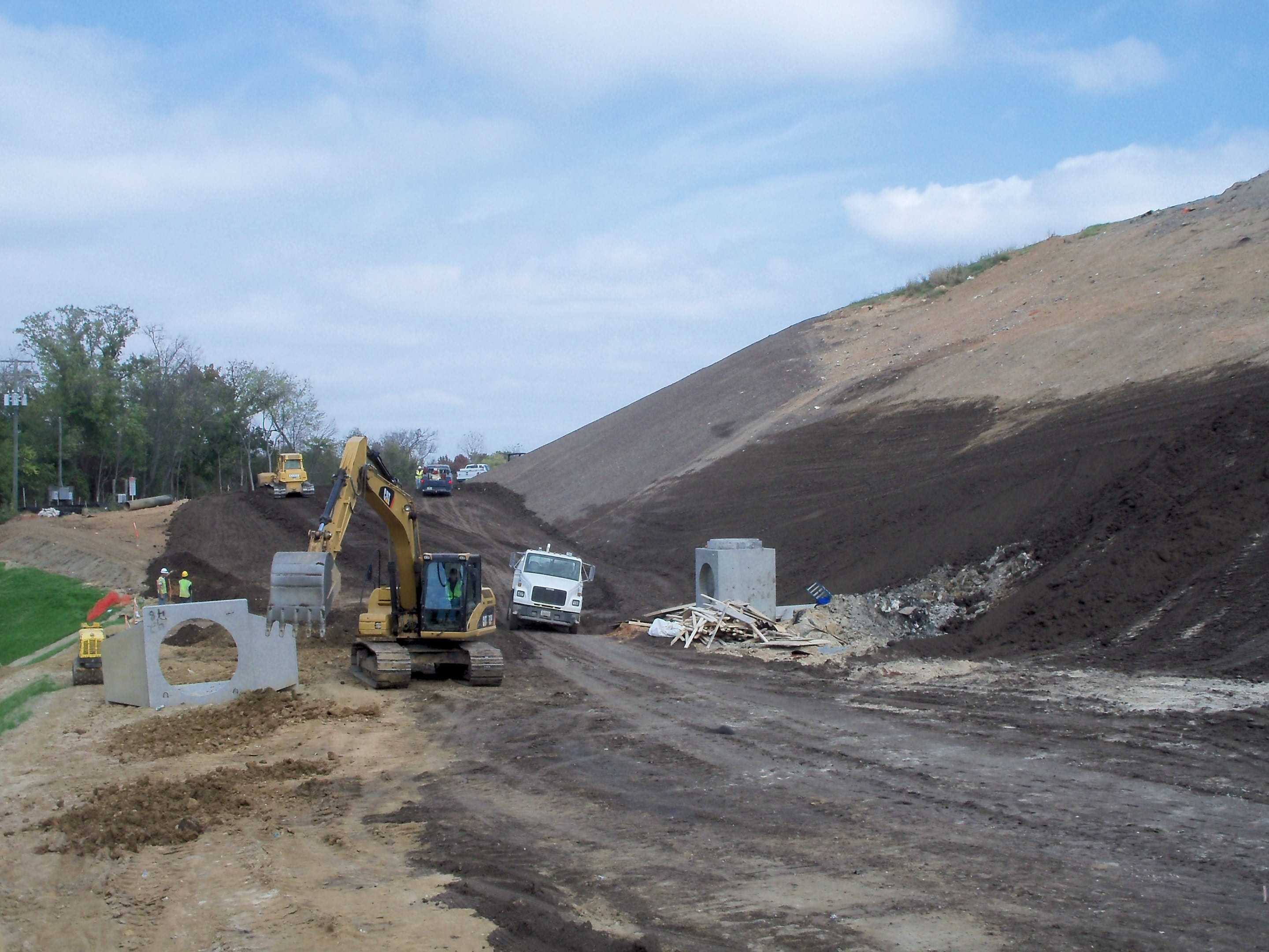 Earthwork construction site with heavy equipment on embankment